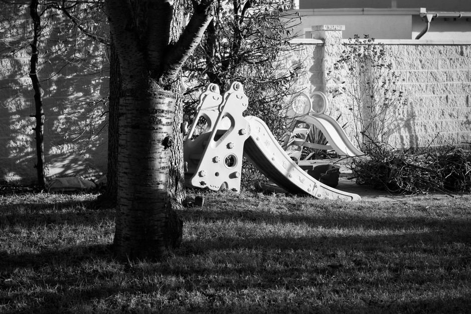 Monochrominiai žaidimų aikštelės kalneliai tarp medžių, sukeliantys vaikystės prisiminimus